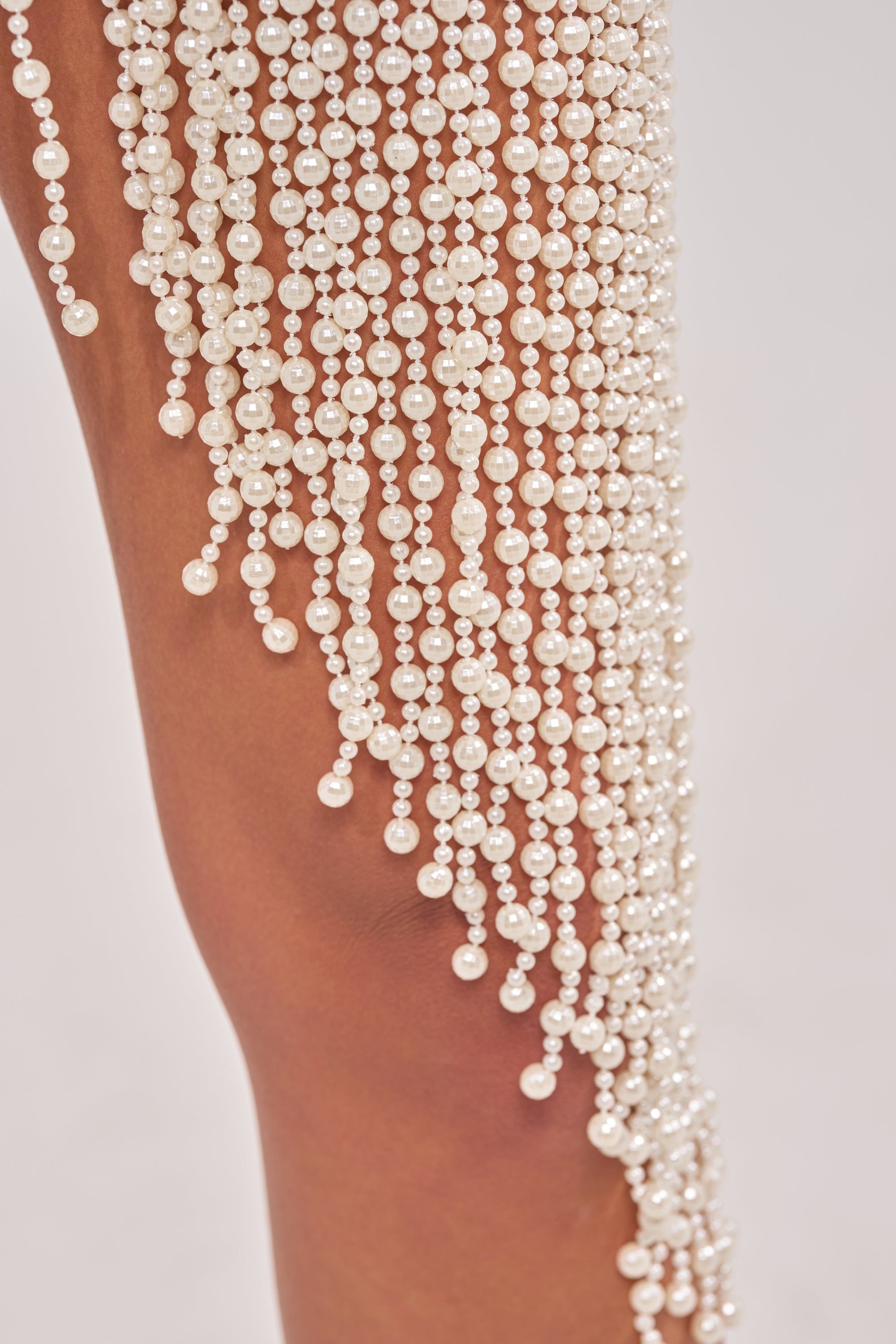 A close-up of white pearl strands draped over a bare leg against a light background, capturing the elegance of the TOGETHER FOREVER BLOUSE WITH PEARLS. 6