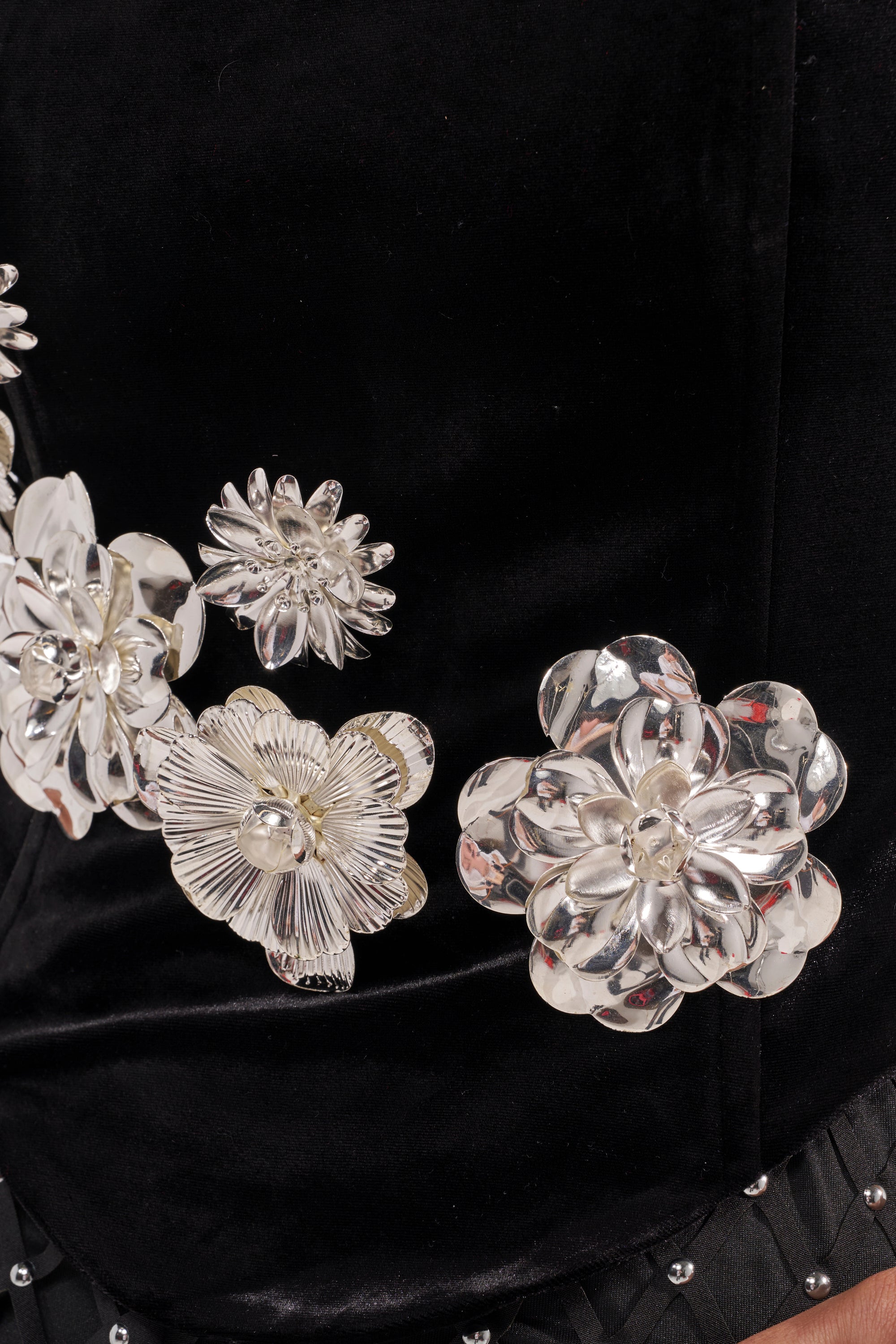 Close-up of the BLINGING OUT CORSET in black velvet, featuring large shiny silver floral embellishments and small round studs along the edge. 10