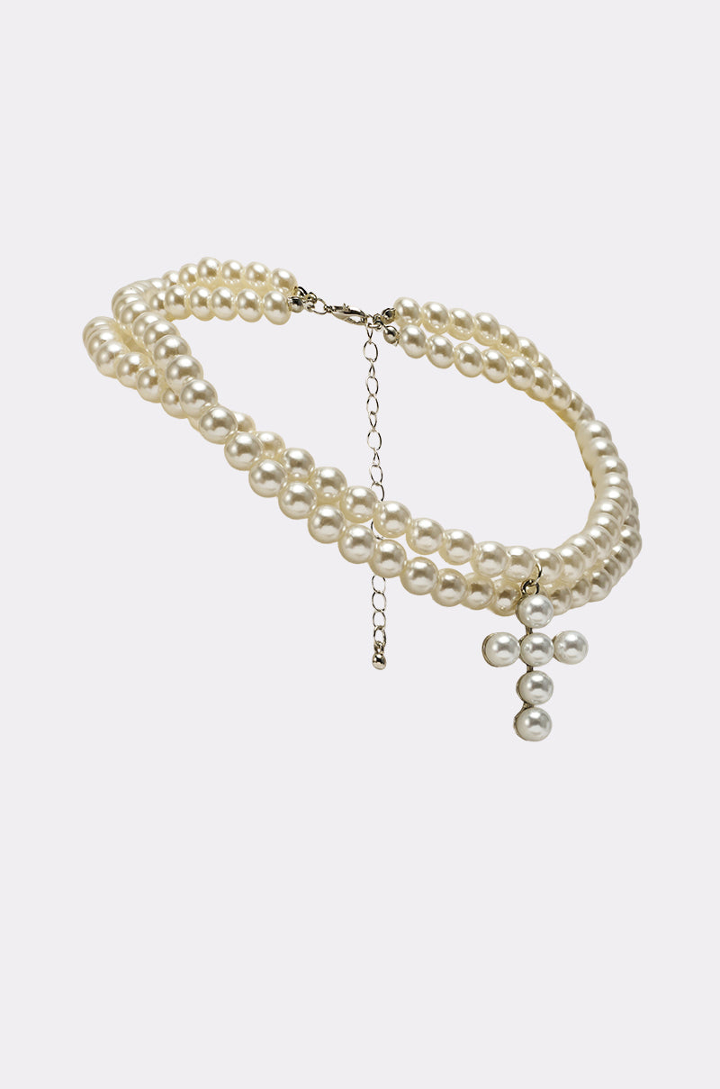 The PEARL DREAMING CROSS CHOKER is a double-stranded layered pearl necklace featuring an adjustable chain clasp and a bold central pearl cross pendant. 2