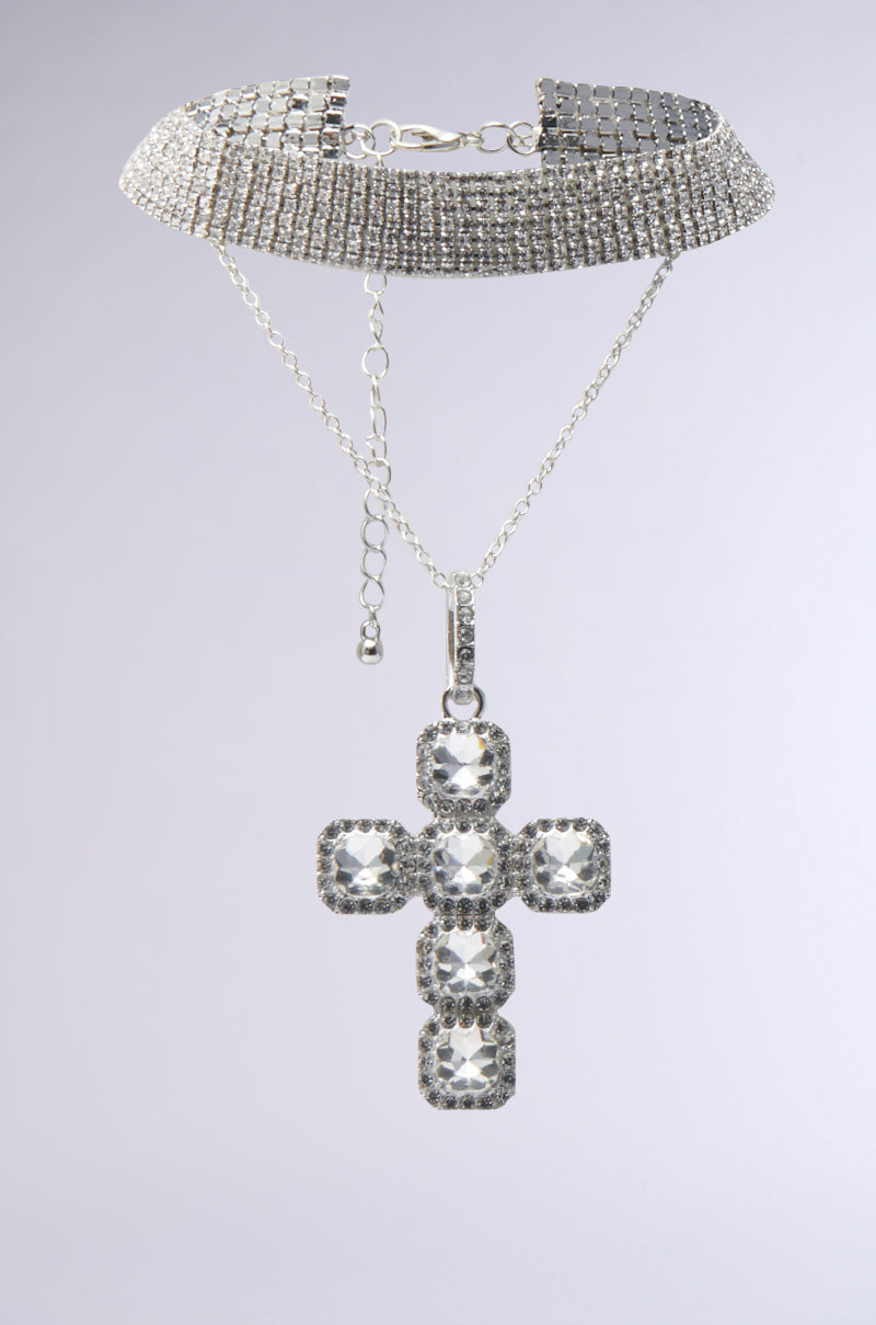 The I AM EVERYTHING SILVER NECKLACE is a sparkling choker with multiple rows of rhinestones and a large jeweled cross pendant, shown against a light gray background.
