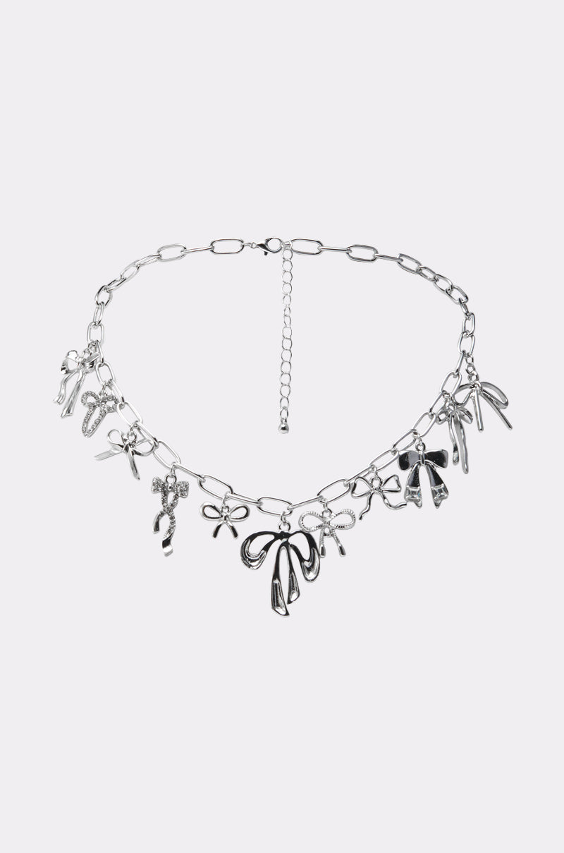The CUTESY NECKLACE features an oversized link chain with festive bow, candy cane, and star charms, showcased against a plain light background.