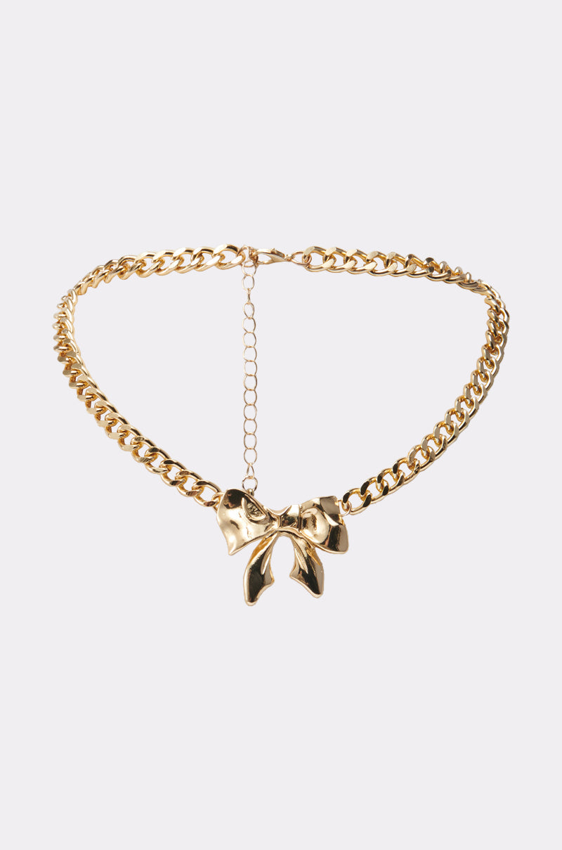 The BELLA NECKLACE showcases a chunky curb link chain in high-quality faux gold, featuring a large shiny bow pendant at the center and an adjustable clasp for a bold statement look. 0
