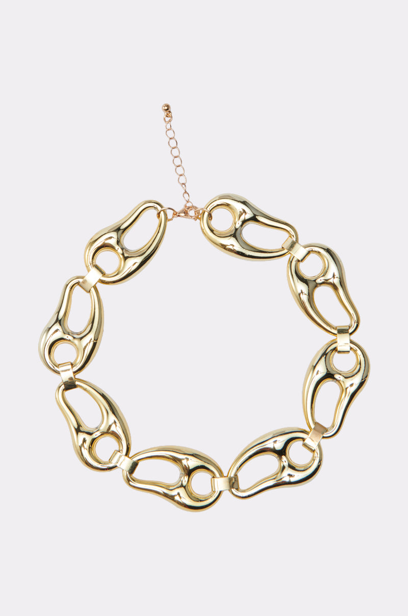 The GATSBY NECKLACE is a gold chunky chain with large, uniquely shaped interlocking links and an adjustable clasp, exuding Art Deco glamour against a plain light background.