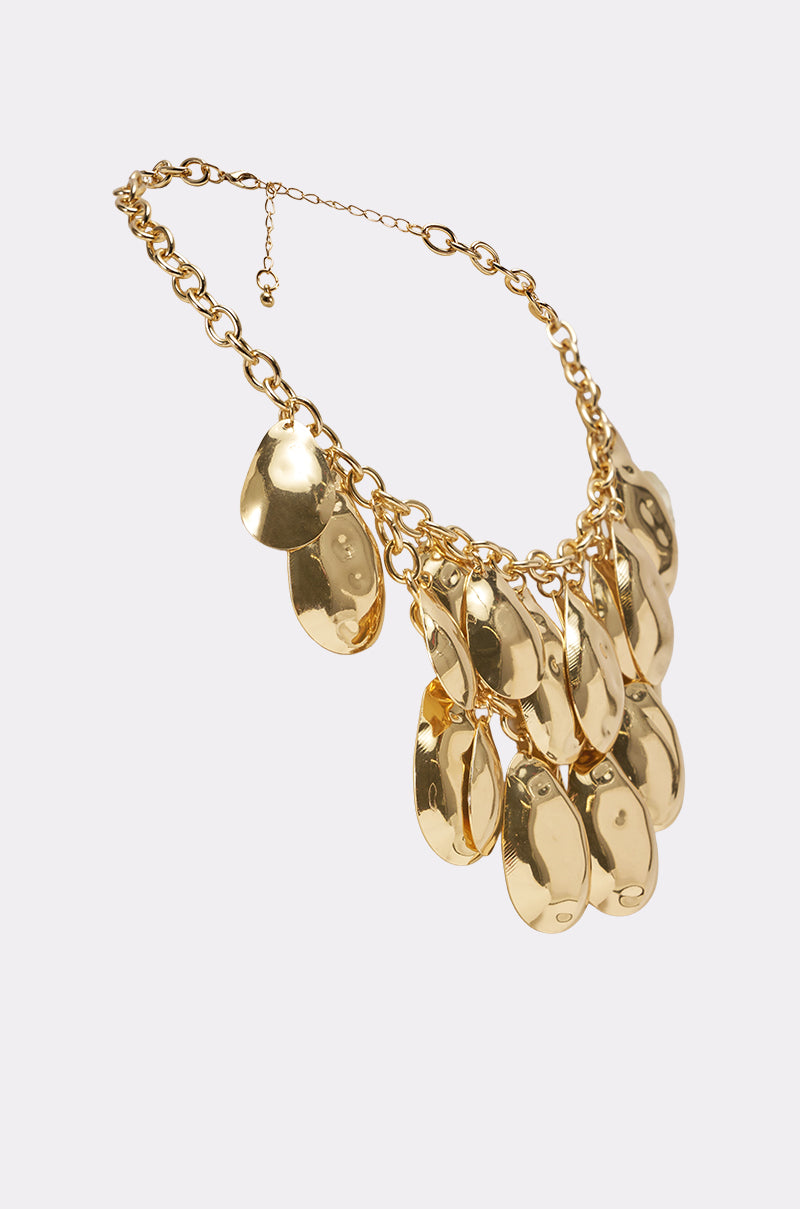 The ON A TRIP NECKLACE features a chunky gold choker with large, shiny oval pendants on a thick, multi-row chain, making a bold statement and highlighting the elegance of a statement curb chain against a plain light background.