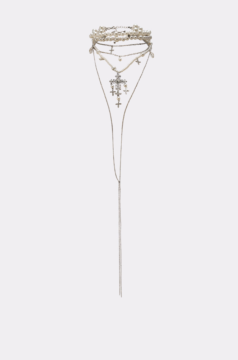 The HERE FOR THE VIBES NECKLACE features multiple layered silver chains with cross charms and bead accents, highlighted by a long center chain for a striking look. 2
