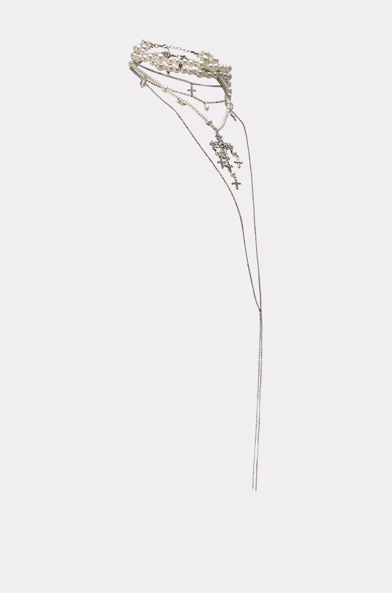The HERE FOR THE VIBES NECKLACE is a delicate silver layered necklace featuring small cross pendants and beaded accents, shown against a plain light background for a refined, stylish look. 4