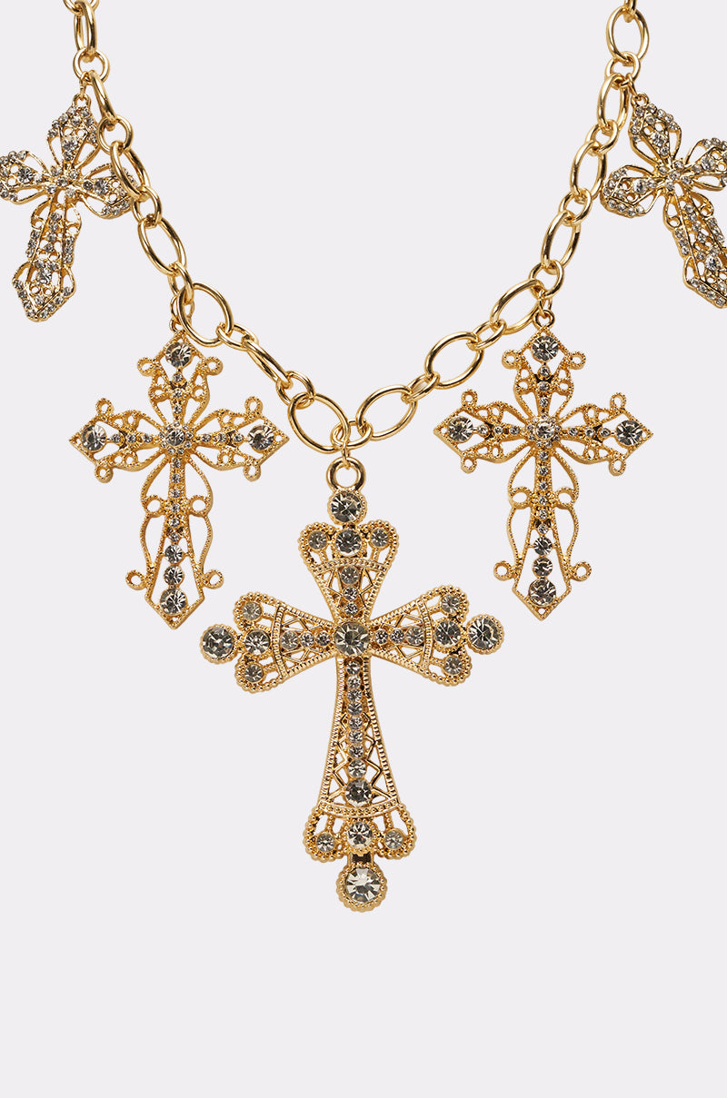 The TAKE A CHANCE NECKLACE features a chunky gold chain with large, ornate cross pendants embellished with intricate filigree designs and sparkling rhinestones. 4