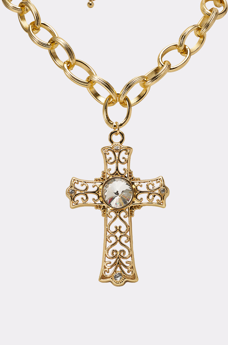 The ALL MY LOVE NECKLACE features an ornate gold filigree cross pendant with a large round crystal at its center, shown on a light background. 3