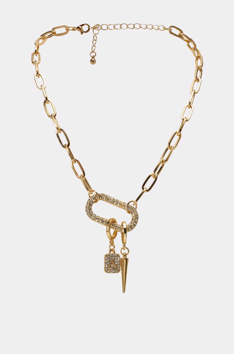The DESIGNER NECKLACE features large gold oval paperclip links, a crystal-studded carabiner clasp, a rectangular charm, circular ring, and spike pendant displayed on a plain light background. 0