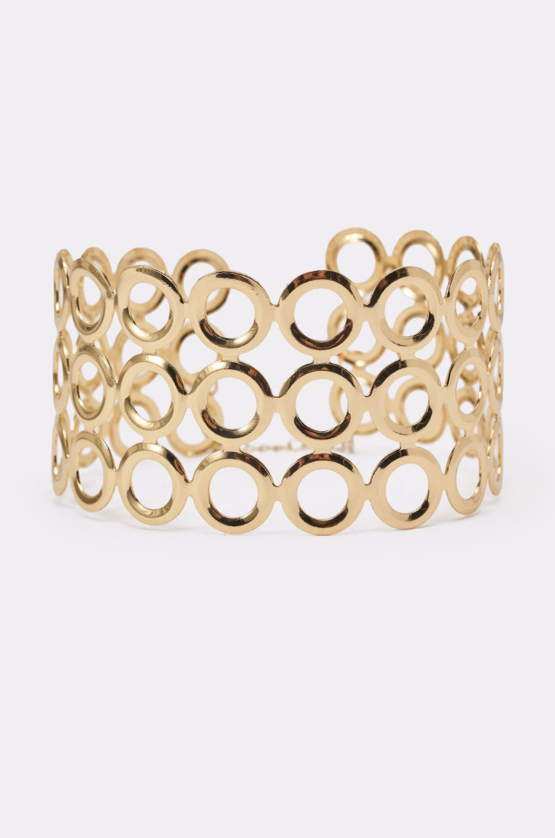 The TITI NECKLACE features three rows of interconnected open circles in a wide gold cuff design with a polished finish, creating a lightweight, geometric look—perfect to pair with your favorite statement necklace. Displayed upright on a plain white background. 2