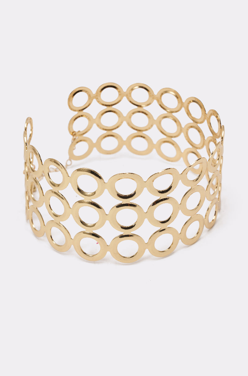The TITI NECKLACE is a striking gold piece with three rows of open oval links, creating a geometric, airy look. It features a shiny finish and an open back for easy wear, reminiscent of bold statement jewelry. 3