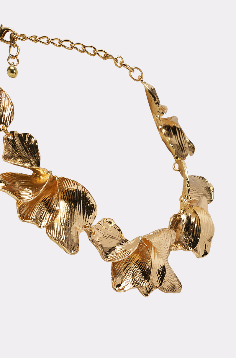 A close-up view of the ON A BEACH NECKLACE in a gold-tone finish, featuring large textured leaf-shaped pendants linked together and finished with an adjustable chain clasp. 3