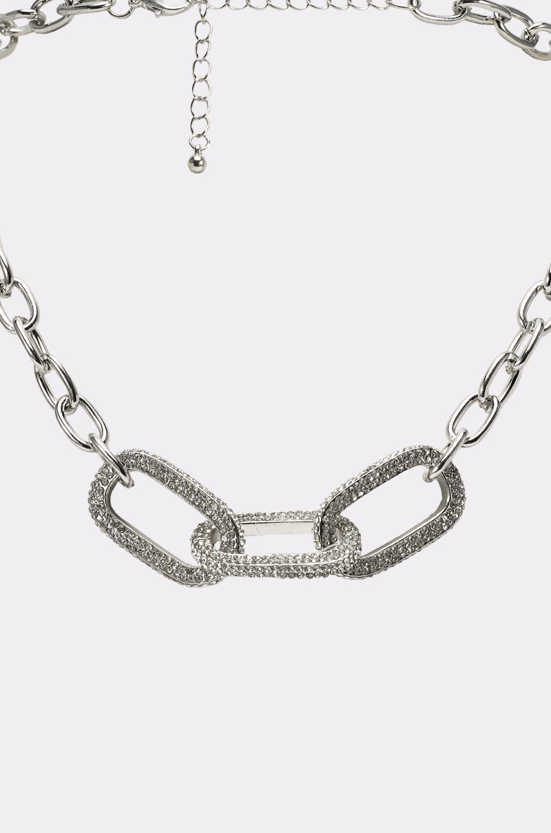 The YA GET ME NECKLACE is a silver statement chain with three large rectangular rhinestone-embellished links at the center, joined by smaller silver links and finished with an adjustable clasp. 2