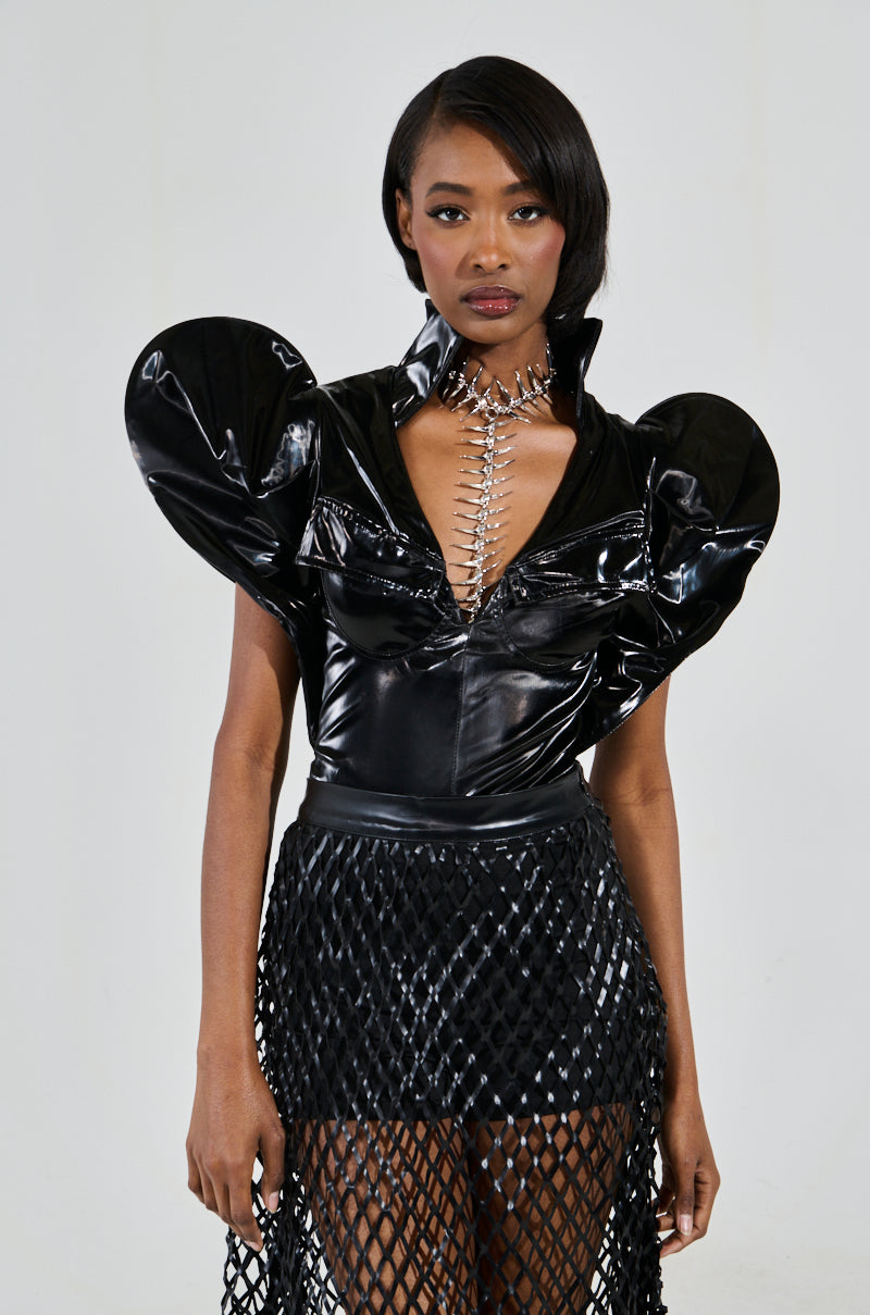 Dressed in the VERONICA DRAMATIC SHOULDER COLLARED BODYSUIT, a person commands attention with a metallic neckpiece and mesh skirt. Their futuristic black attire, featuring voluminous shoulders, captivates against the neutral background. 2