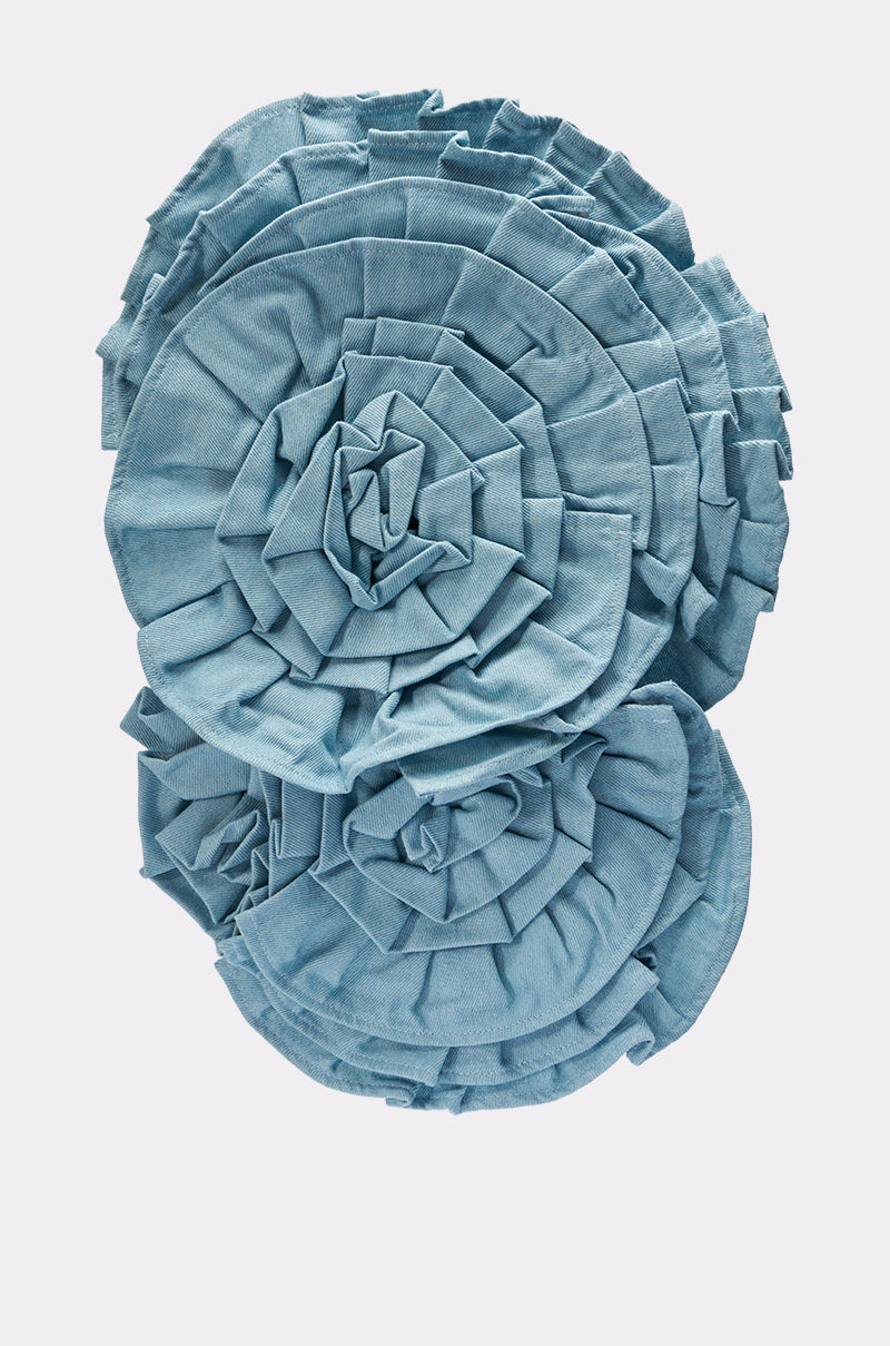 Three large, overlapping SO FINE DENIM BROOCHES in light blue—each with layered, ruffled, petal-like folds—are arranged on a plain white background like oversized fabric flowers.