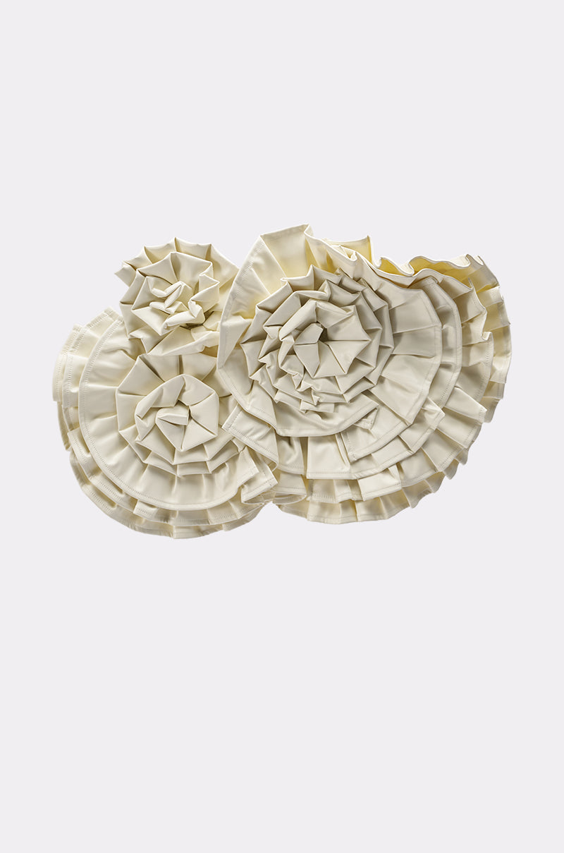 The BLOOMING PU OVERSIZED BROOCH features three cream folds arranged in overlapping circles, resembling floral brooches or abstract rosettes, creating a stunning statement on a plain background. 4
