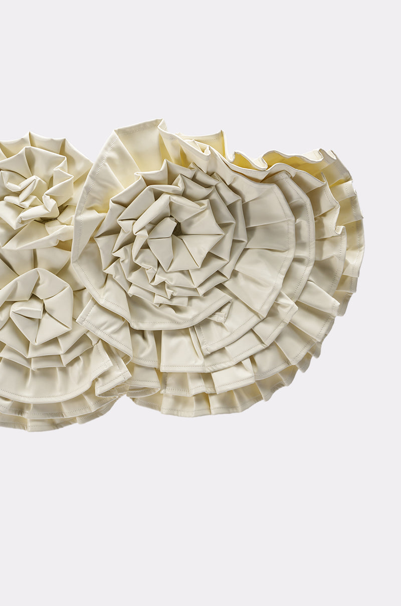 Close-up of the BLOOMING PU OVERSIZED BROOCH, featuring intricately folded cream-colored faux leather arranged in a circular, floral pattern with layered, pleated edges against a plain light background. 6
