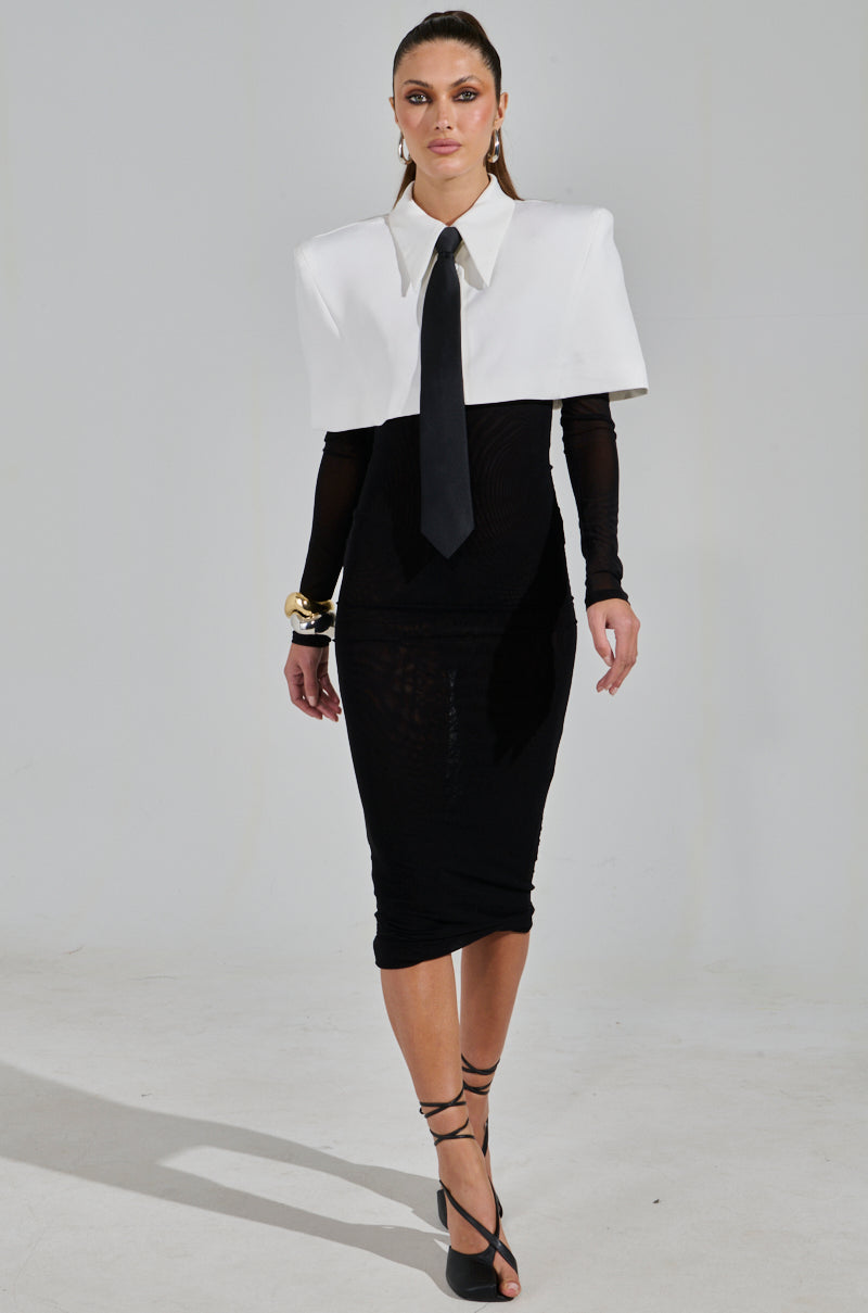 A model showcases a striking look with a cropped blazer over the SHE MEANS BUSINESS TIE DETAIL MESH MIDI DRESS, paired with black strappy heels and gold bracelets against a plain white background, highlighting its elegance and modern charm.