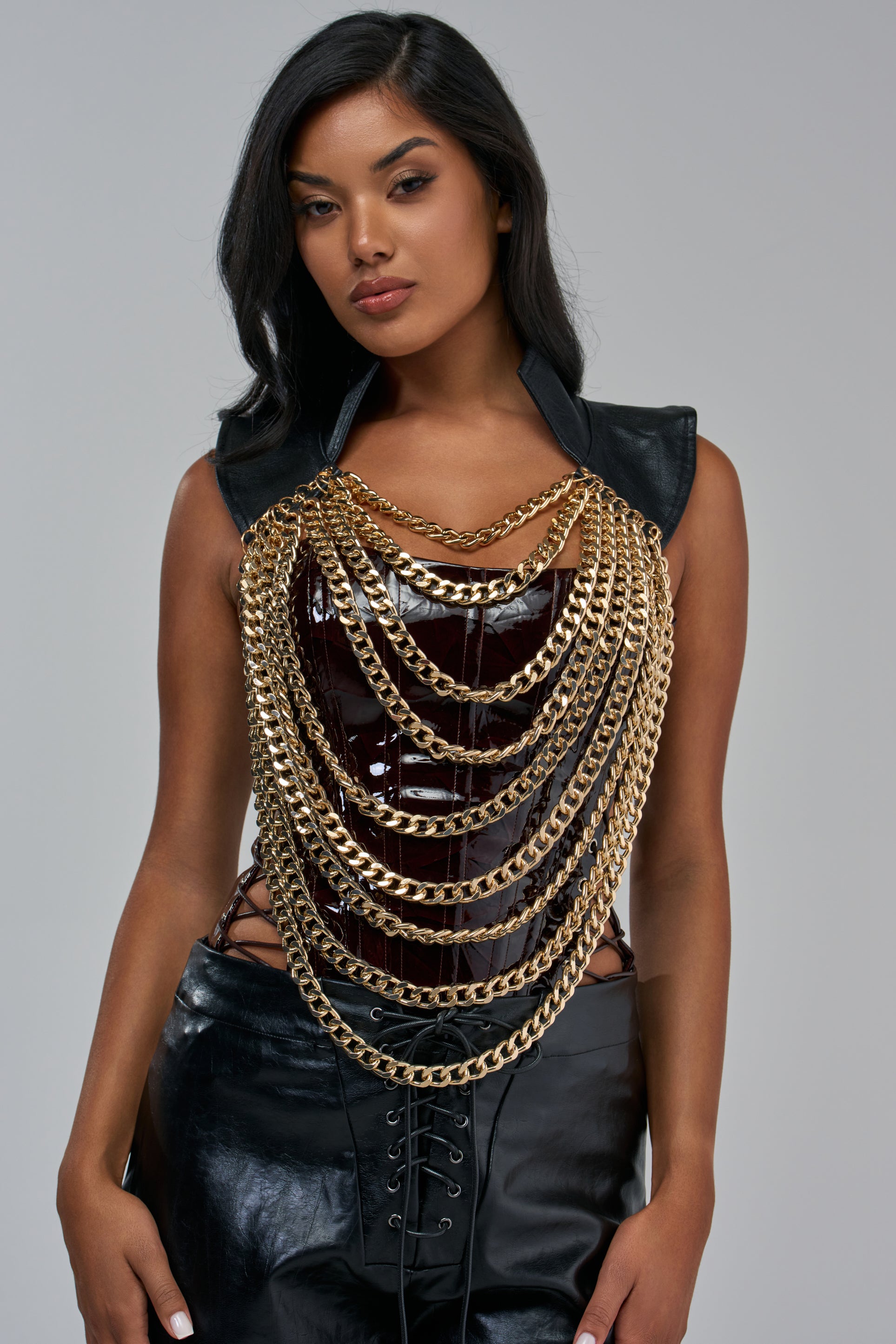 A woman wears a layered HEAVY METAL NECKLACE IN BLACK over a dark, glossy corset top.