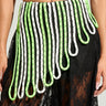 A person wearing the SPORTY CHIC STRETCH BELT, which complements a distinctive skirt with a sporty chic vibe. The skirt features a striking white and neon green rope pattern over black lace fabric, with long, looped ropes cascading down to create an eye-catching texture.