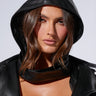 A person with shoulder-length brown hair wears the COOL GIRL AESTHETIC HOOD, exuding a cool girl vibe as they look directly at the camera. The plain, light-colored background complements the model's outfit and facial features.