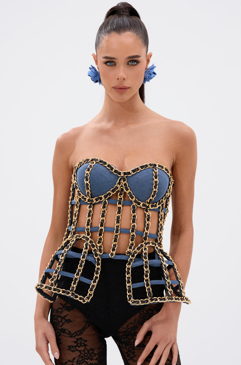 A woman with blue eyes and a high ponytail models the DOWN SOUTH CHAIN DETAIL BUSTIER TOP, paired with black lace shorts and blue flower earrings, against a plain white background. 2