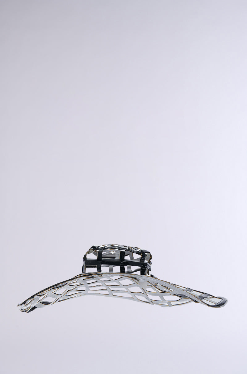 Introducing the IM OFF THE GRID BLACK SILVER HAT, a modern and futuristic accessory featuring an oversized brim and an intricate open lattice structure. Adorned with a sleek black band made of faux leather, this minimalist yet elegant hat elegantly stands out against a plain gray background, seamlessly blending stylishly forward-thinking design with timeless allure.