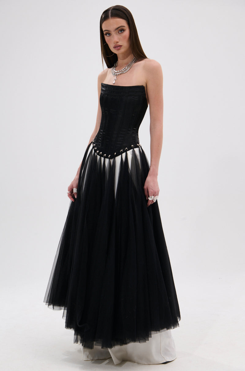 A woman wears the MARRIED TO THE GAME CORSET TOP IN BLACK, styled strapless with a full tulle skirt, white hem detail, layered silver necklaces, and a lace-up back, standing against a plain white background.