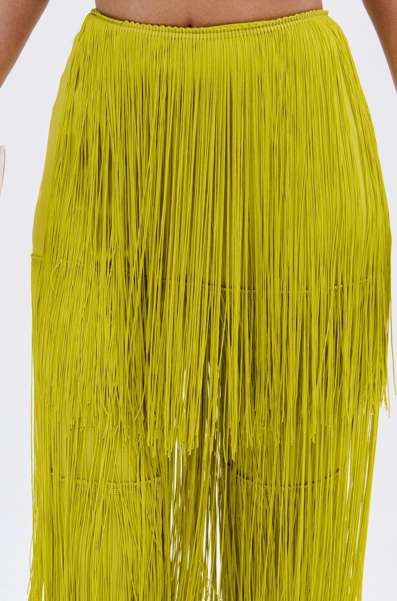 Close-up of a person wearing the OH SO FRINGE PANTS IN GREEN, featuring a high-rise fit and bright yellow-green fringe with long, textured layers against a plain white background.