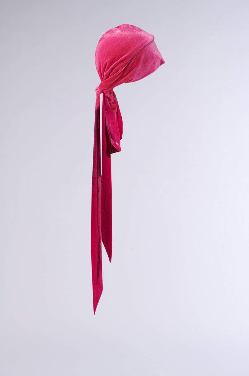 The RAY VELVET DURAG in pink features long, trailing ends tied in a loose knot, shown against a plain light gray background.
