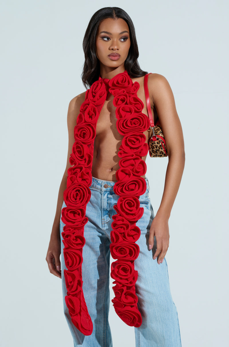 A woman wears light blue jeans and the statement-making EXTREME LENGTHS ROSE NECKLACE with no shirt underneath, carrying a leopard print bag over her shoulder, embodying wearable art against a plain light background.