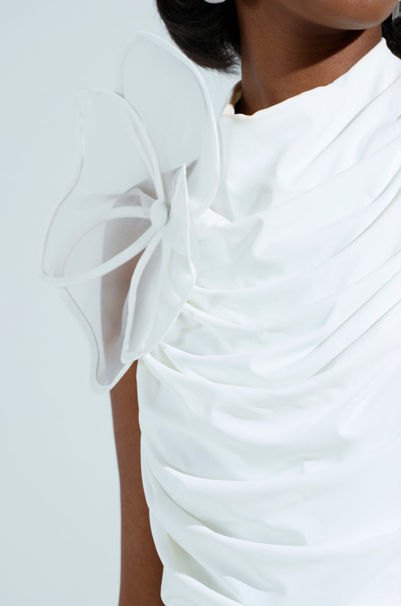 Close-up of a person in the IN BLOOM BROOCH SET featuring a white, sleeveless dress with ruched fabric and sheer unlined mesh. The outfit showcases a large translucent flower detail on the shoulder, complemented by flower-shaped appliques, against a soft, light background. 5