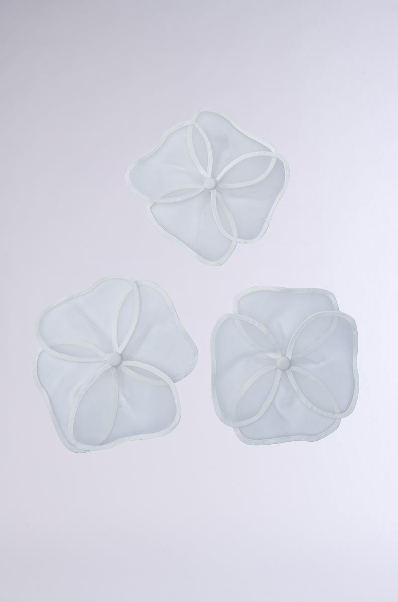 Three translucent mesh laundry bags, shaped like flowers, are elegantly displayed on a light gray background. The petal-like design and round center resemble the IN BLOOM BROOCH SET, creating a whimsical appearance. 9