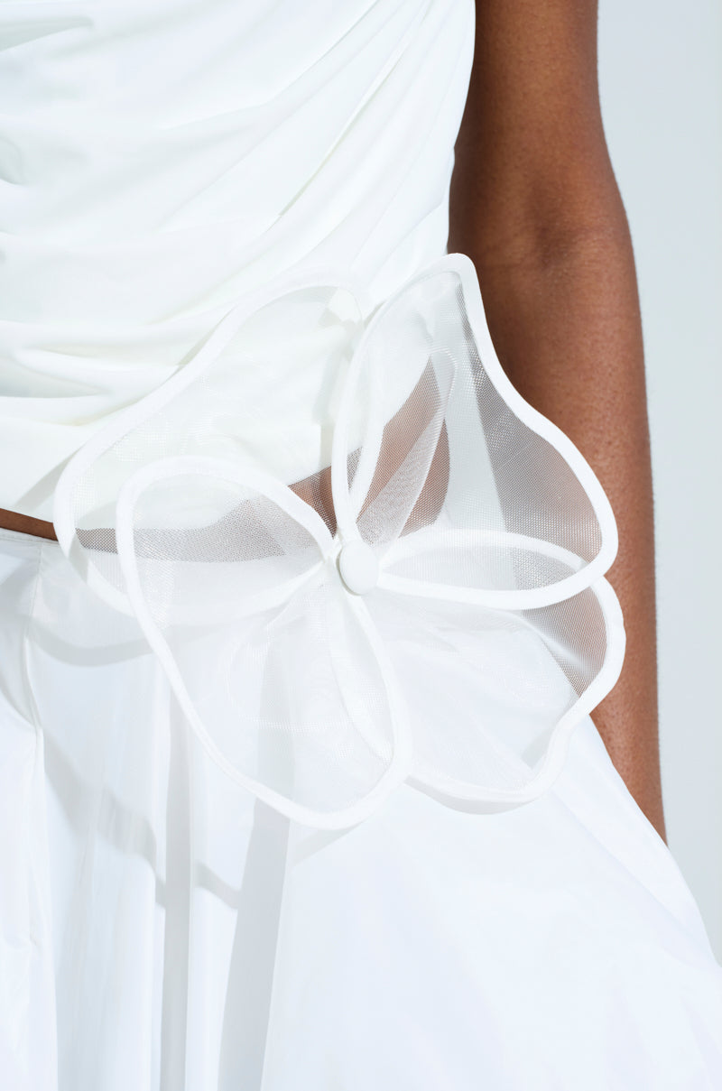 Close-up of someone wearing the IN BLOOM BROOCH SET, showcasing a smooth white outfit with sheer unlined mesh and a large decorative flower at the waist, adding an elegant touch. 7