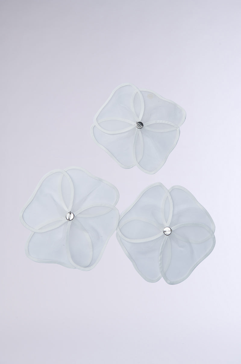 The IN BLOOM BROOCH SET, with its translucent petal-like design and central metallic accents, resembles delicate overlapping flower petals against a plain background. 10