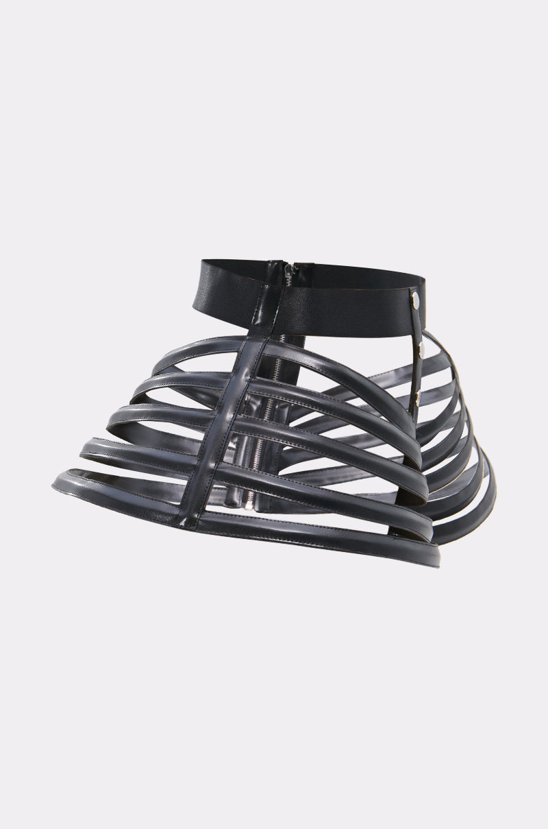 The DRAMA STRETCH CAGE BELT is a black, high-rise faux leather skirt featuring multiple horizontal straps and a structured open-frame design, shown against a plain white background.