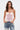 A woman with wavy brown hair models the GOING PLACES CORSET WITH TWEED, a pastel pink strapless top with structured details, paired with light blue jeans featuring lace and 
