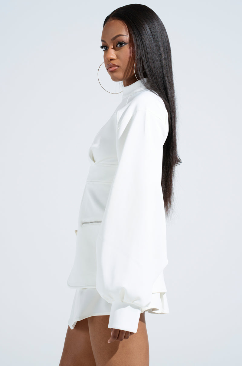 With long, straight hair, the person dons the YOU WISH YOU WERE ME BLOUSE TOP featuring a mock neck and long sleeves. Large hoop earrings add flair to this elegant ensemble, as they stand in profile against a plain background.