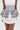 Wearing a white dress with the POLKA DOT IT BELT and ruffled black-and-white striped layers, someone creates a playful, bold contrast. The photo is cropped from the shoulders down.