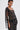 A woman with short dark hair models the ONLY ONE OF ME RHINESTONE MIDI DRESS, showcasing its geometric black and white spiral patterns and rectangular shapes. She completes the look with dangling earrings against a plain white background.