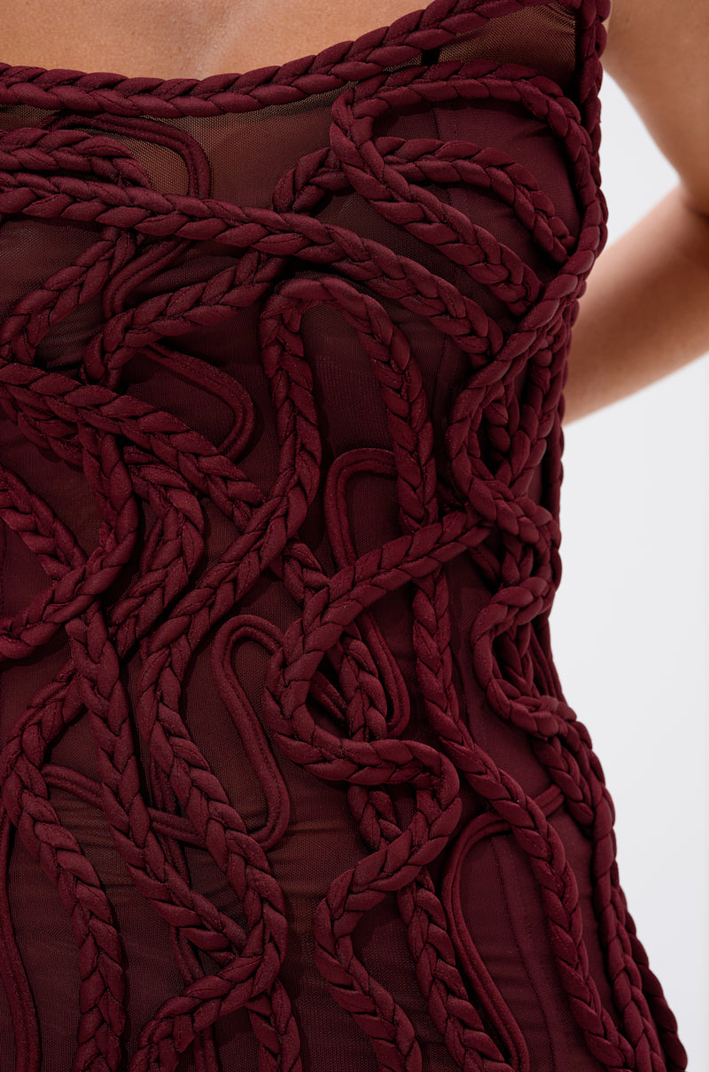 The ALL OVER THE PLACE BRAIDED MINI DRESS features thick, rope-like braids woven across sheer burgundy mesh for a textured, three-dimensional look.