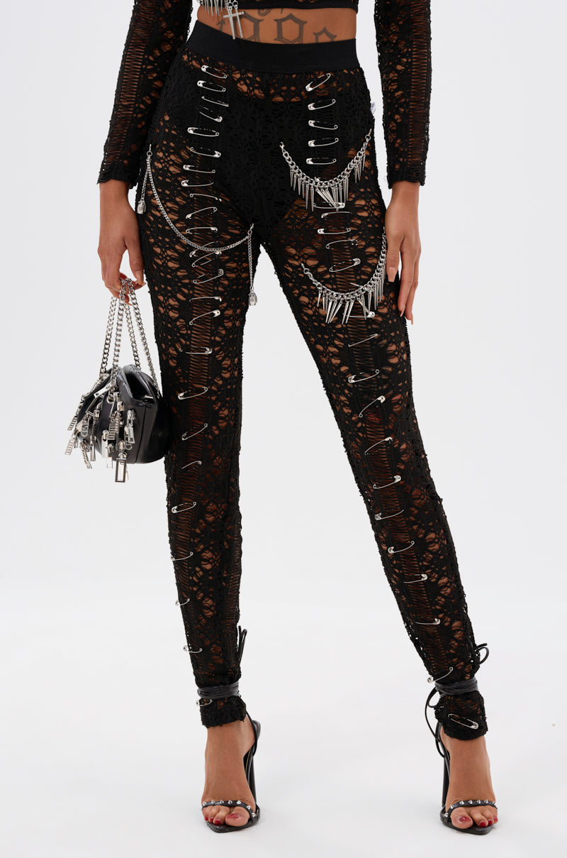 Wearing edgy TRY ME LACE LEGGING adorned with safety pins and silver chains, styled with high heels and a small black metallic-detailed handbag. Photo is cropped from shoulders down.