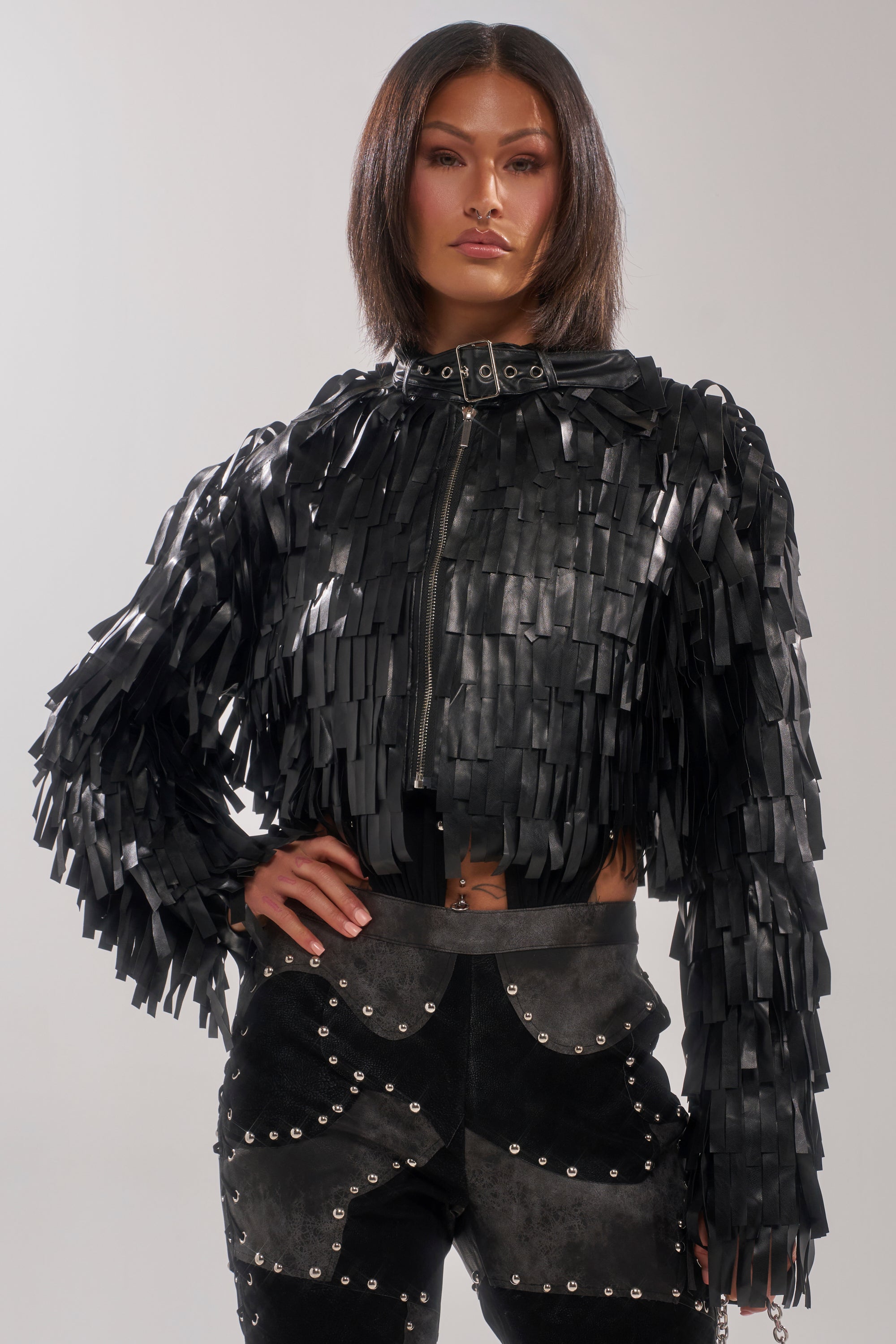 A person with straight, shoulder-length hair wears the RIDE EM FRINGE MOTO jacket and black metallic-accented pants, posing confidently with one hand on their hip against a neutral background.
