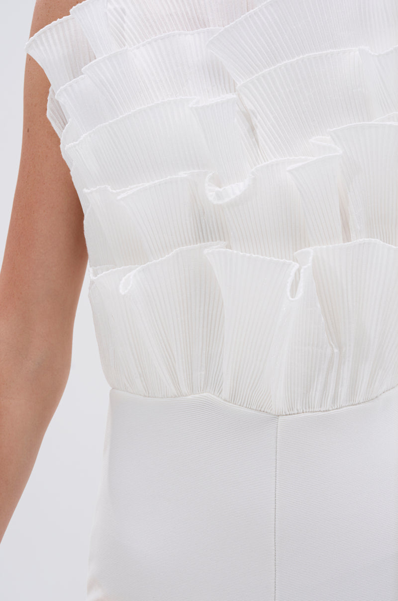 Close-up of a person wearing the ADA RUFFLE TOP BANDAGE JUMPSUIT, highlighting sculptural mesh organza ruffle details on top and a smooth, fitted lower half. Only part of the arm and back are seen against a plain background. 5