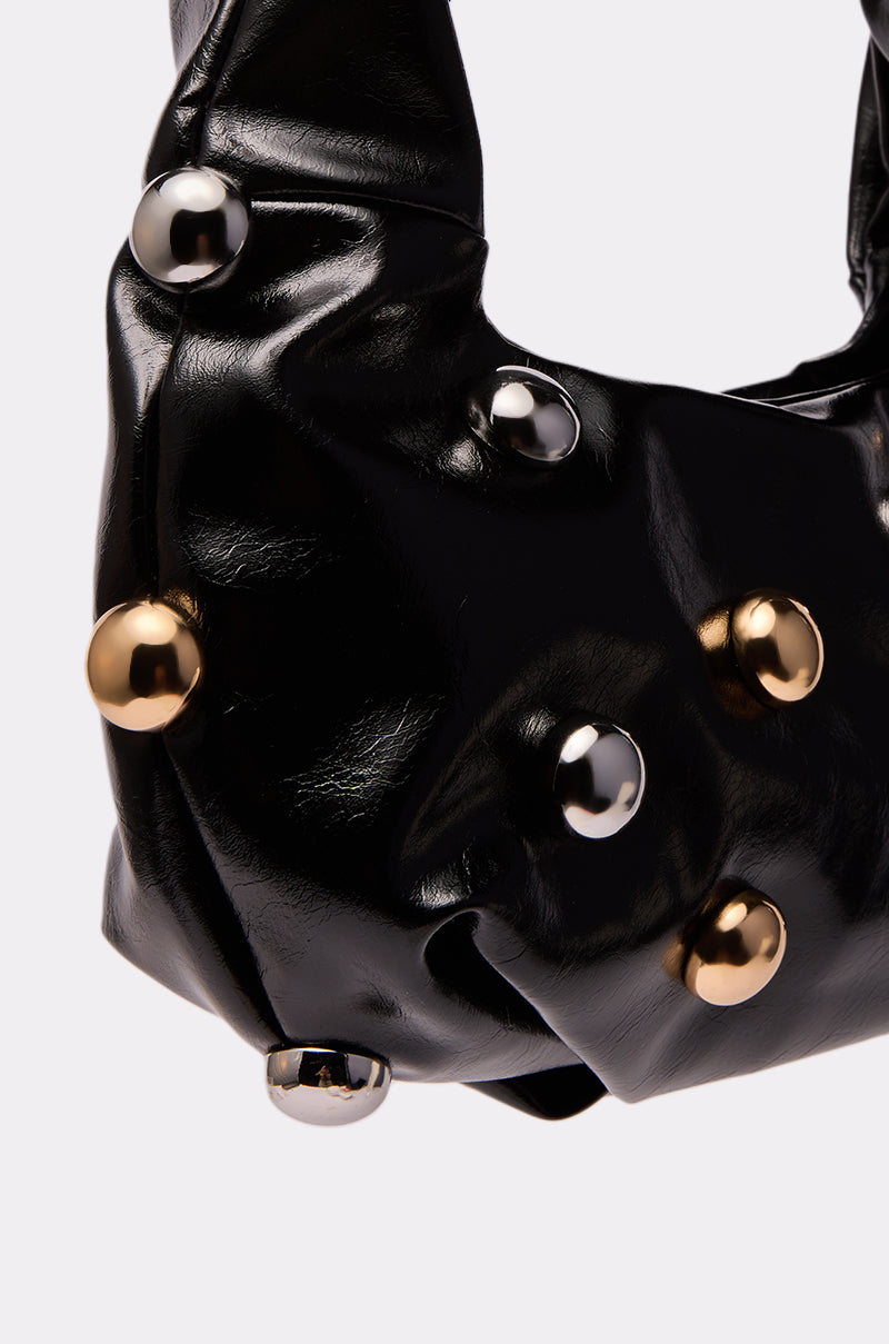 Close-up of the TOO MOD BALL PURSE, a black faux leather bag adorned with metallic gold and silver round studs, set against a plain light background. 3