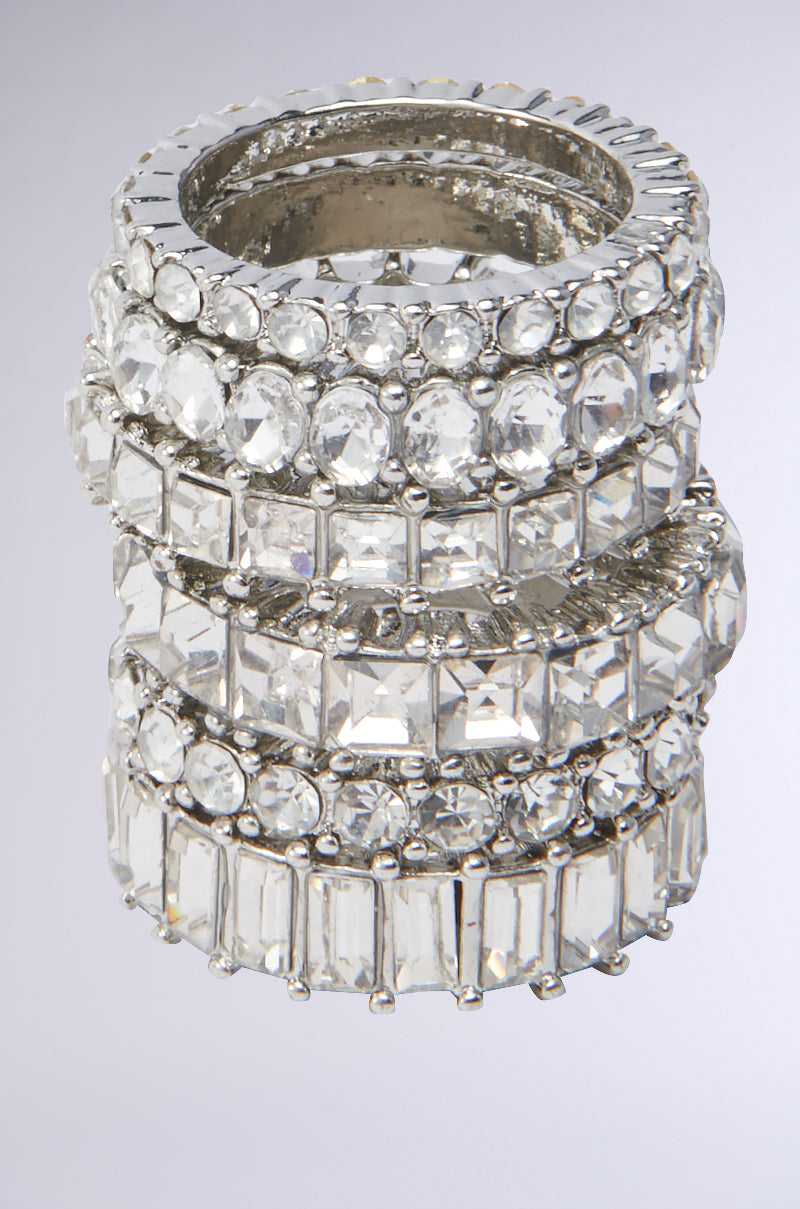 The SPEND IT RHINESTONE RING SET features five silver-tone bands decorated with clear round, square, and rectangular gemstones for an eye-catching stacked shine.