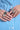 A close-up of manicured hands displays four large, intricately designed YUCK RINGS on different fingers, each in faux silver. The person wears a blue and white striped shirt with white buttons, capturing the edgy elegance of the AKIRA Label.