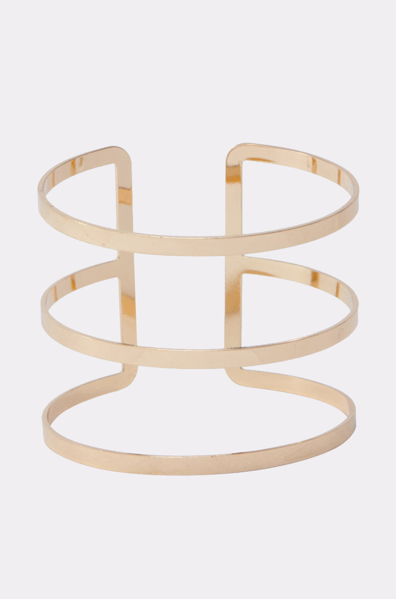The STRICTLY BUSINESS ARM CUFF features three horizontal bands joined by two vertical bars, forming a sleek open geometric design with a polished gold finish and open back—ideal for elevating any outfit. 0