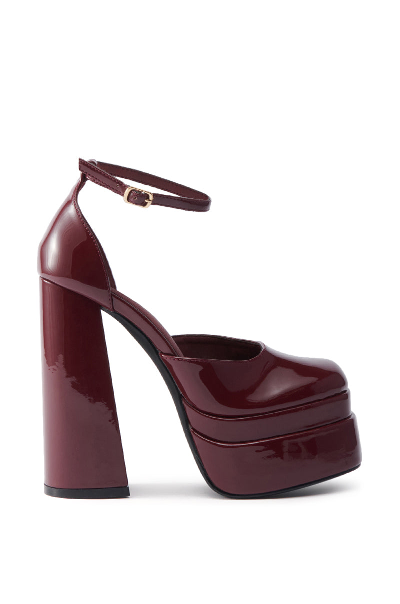 The AZALEA WANG YUFFIE PATENT BURGUNDY PUMP features a shiny dark burgundy finish, chunky heel, platform sole, rounded toe, and an ankle strap with a small buckle.
