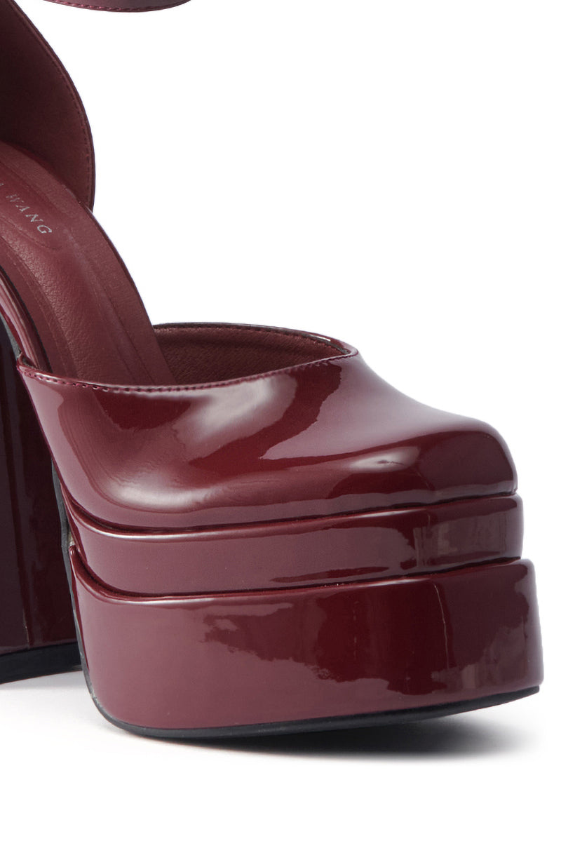 The AZALEA WANG YUFFIE PATENT BURGUNDY PUMP features glossy patent leather, a platform sole, and a chunky heel, highlighting the rich texture and shine of its burgundy finish.